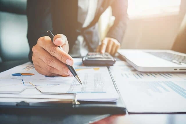 Bookkeeping Business-hands busy with pen and calculator checking numbers on forms