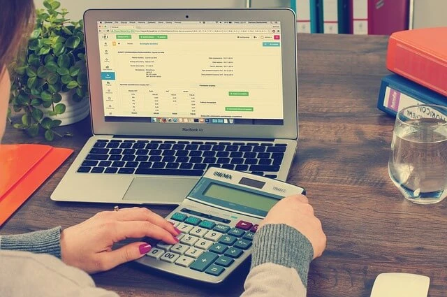 Bookkeeping Business-laptop with numbers and hands using calculator