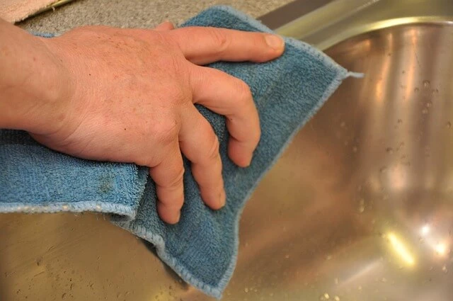 House Cleaning-woman's hand wiping steel sink