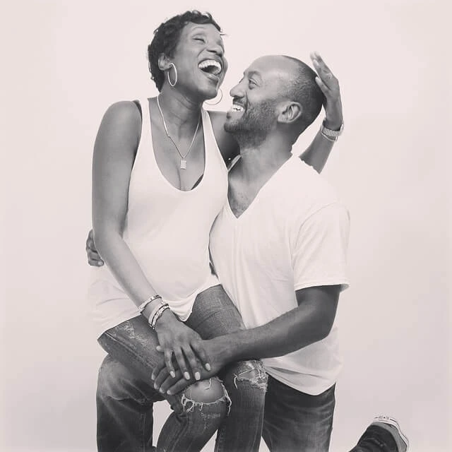 Photography Business-black and whit photo of young black couple with woman sitting on man's knee-both laughing