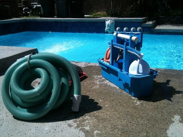 Pool Cleaning Business-Pool cleaning hose and caddy of chemicals by swimming pool